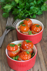 Vegetarian food: Mediterranean style baked tomatoes stuffed with feta cheese, chickpeas and herbs in red pan on wooden background