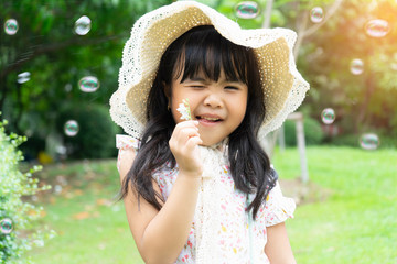 Happy Asian portrait little girl play with soap bubbles and sunlight summer in park outdoor