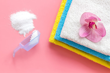 Laundry concept. Clean linen and orchid near washing powder on pink background top view