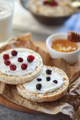 Cereal bread rolls with curd cheese and currant and cranberry berries, closeup. Proper and healthy nutrition.