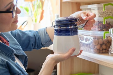 Woman in the kitchen with can of dry mint, food storage, pantry