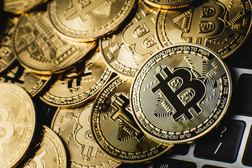 Groups of bitcoin is perched on the keyboard of the laptop. Crypto currency concept.