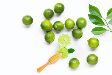 Fresh limes and leaves with wooden juicer on white background.