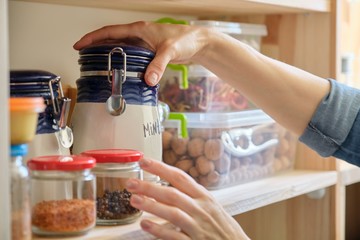 Woman in the kitchen with can of dry mint, food storage, pantry - obrazy, fototapety, plakaty