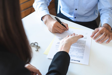 Real estate brokers point to a contract paper with their hand and advise customers to sign their names. Real estate agent, Broker concepts.