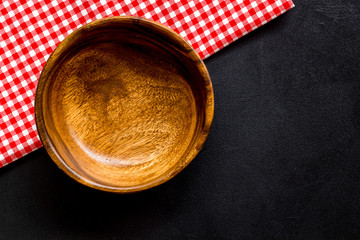 Preparing for lunch - empty wooden bowl closeup on black background top view copy space