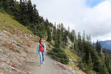 Happy woman walking along a mountain trail near Mount Rainier, Washington State, USA 
