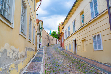 Narrow, empty, cozy street of an old European city with houses and a wall