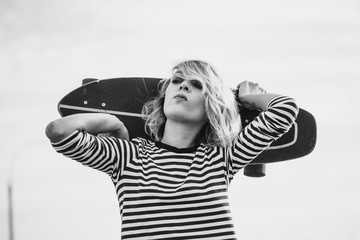 Urban stylish young sportive woman walking with skateboard. Close up portrait of a pretty young...