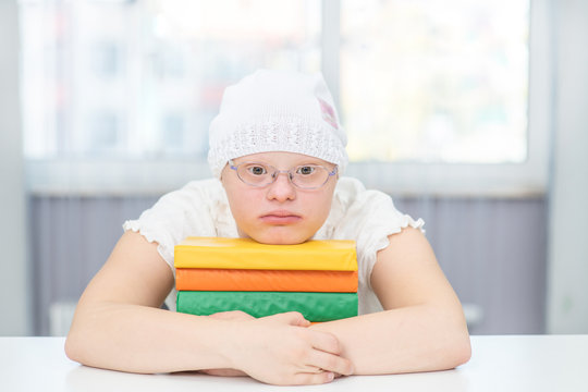 Young girl with Down Syndrome with books at home