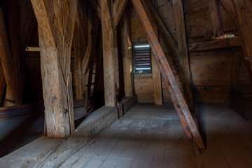 Empty loft of an old wooden building with beams made of thick wooden materials.