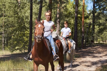 Group of teenagers on horseback riding in summer park