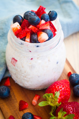Spring colorful homemade oat porridge with fresh strawberries and blueberries made of buttermilk