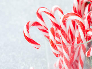 Christmas candy sticks on glass with silver bokeh background.