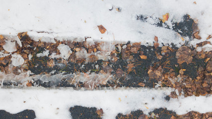 Tire tracks in the melting snow on asphalt road