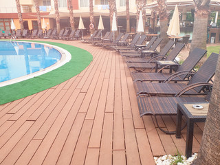 Swimming pool, sunbeds and folded sun umbrellas in the sunny summer morning