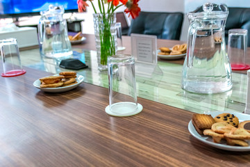 Business people sitting on a table for conference with cookies glass and jar of water placed on wooden table
