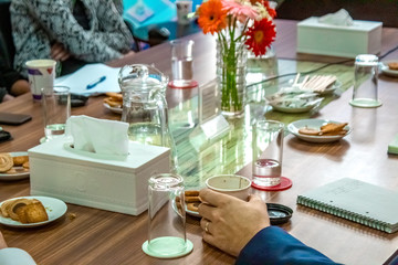 Business people sitting on a table for conference with cookies glass and jar of water placed on wooden table