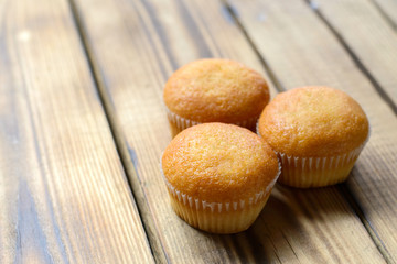 Three cupcakes with different fillings, side view, on wooden background.