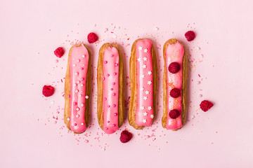Creative layout made of eclairs with pink glaze on pink background. Monochrome Food concept