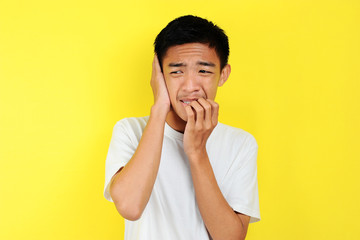 Fototapeta na wymiar Portrait of young Asian teenager unhappy scared man, isolated on yellow