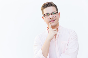 Pensive entrepreneur touching chin and looking away. Young man in glasses standing isolated over white background. Thinking or planning concept
