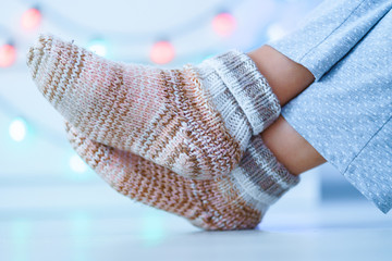 Resting female in warm knitted soft comfortable socks in wintertime at home.