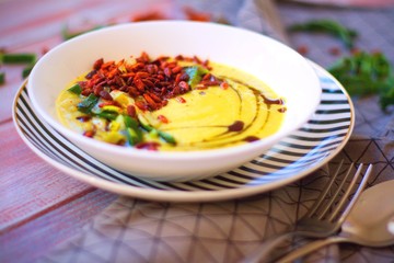 Spring leek cream soup with potatoes and roasted paprika seasoned sunflower seeds in white bowl on striped plate.