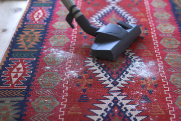 cleaning service cleans the apartment. housewife vacuuming red carpet at home