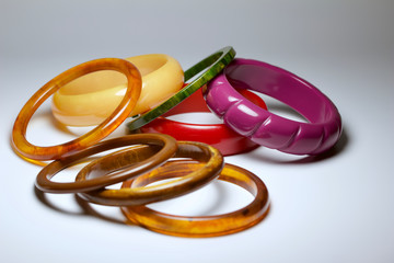 Close up view of vintage bakelite bangle bracelets in varying colors and widths on white background