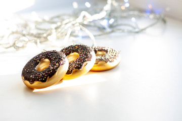 Three Christmas toys donuts on a white background, in the background Christmas garland
