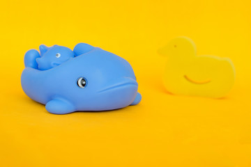 baby bath accessories on a yellow background, blue dolphins and a yellow duck-shaped sponge