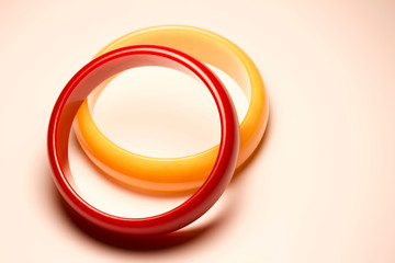 Close up view of a pair of red and yellow vintage bakelite bangle bracelets on white background