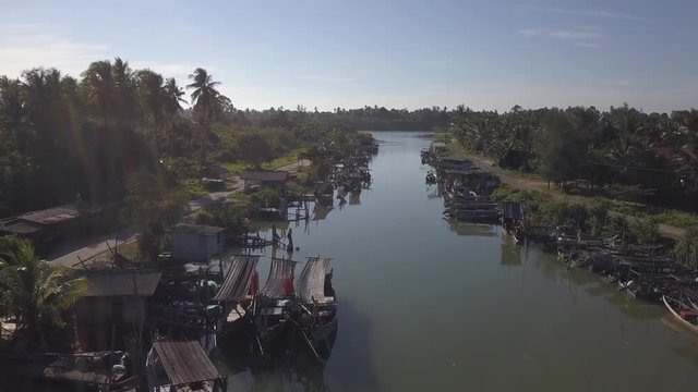 Aerial view of fisherman village with boats dock at the river estuary nearby.