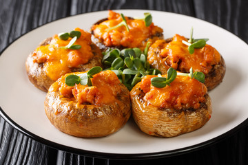 Baked hot mushrooms stuffed with minced meat and cheddar cheese close-up on a plate. horizontal