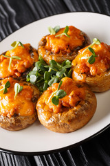 Baked Portobello mushrooms with minced meat and cheddar cheese close-up on a plate. vertical