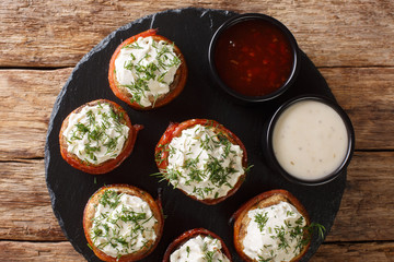 Baked mushrooms with cream cheese wrapped in bacon served with sauces close-up on the table. horizontal top view