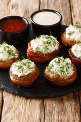 Mushrooms stuffed with cream cheese wrapped in bacon close-up on a plate. vertical