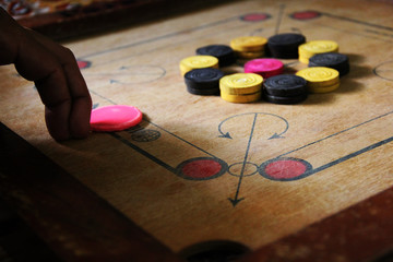 A game of carrom with pieces carrom man on the board carrom.Carom board game, selective focus.