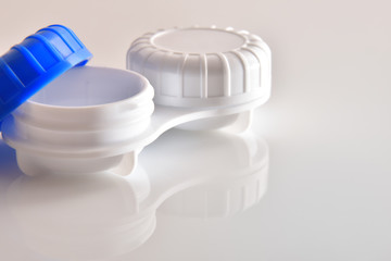 Contact lens case open reflected on white glass table