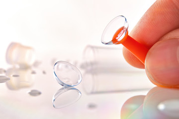 Fingers catching a lens with an applicator on table