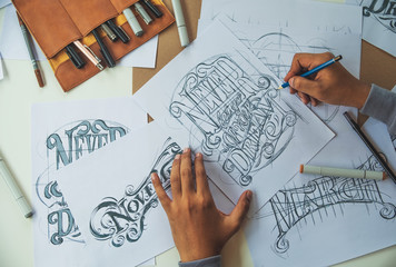Typography Calligraphy artist designer drawing sketch writes letting spelled pen brush ink paper table artwork.Workplace design studio.