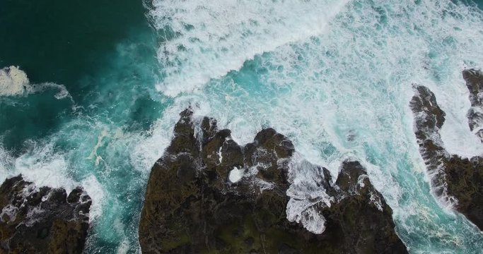 A wide angle high perspective aerial drone shot of the mighty Thor&rsquo;s Well as the barnacle encrusted hard volcanic rock shelves of the area get overrun by beautifully power teal and blue ocean waves