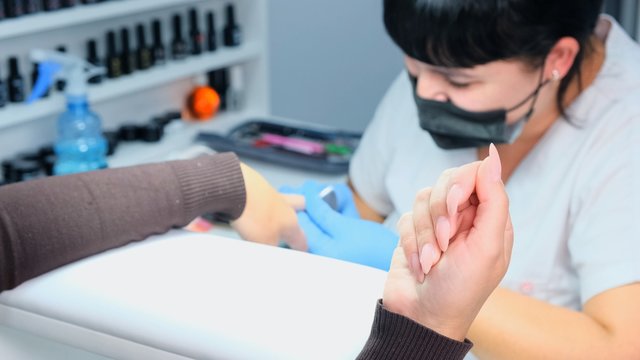 Manicurist files a nail with a nail file to a client. Manicure process, nail extension. close-up
