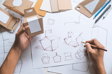 Designer sketching drawing design Brown craft cardboard paper product eco packaging mockup box development template package branding Label . designer studio concept .
