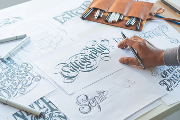 Typography Calligraphy artist designer drawing sketch writes letting spelled pen brush ink paper...