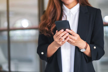 Closeup image of a businesswoman holding and using mobile phone