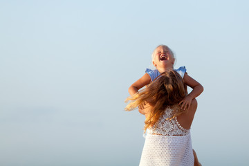 Fototapeta na wymiar Portrait of happy sisters. They hug on the background of the sea.