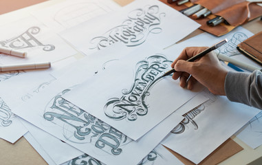 Typography Calligraphy artist designer drawing sketch writes letting spelled pen brush ink paper table artwork.Workplace design studio.