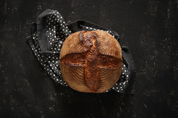 Freshly baked Artisan sourdough bread loaves with kitchen towel on black concrete backgroun